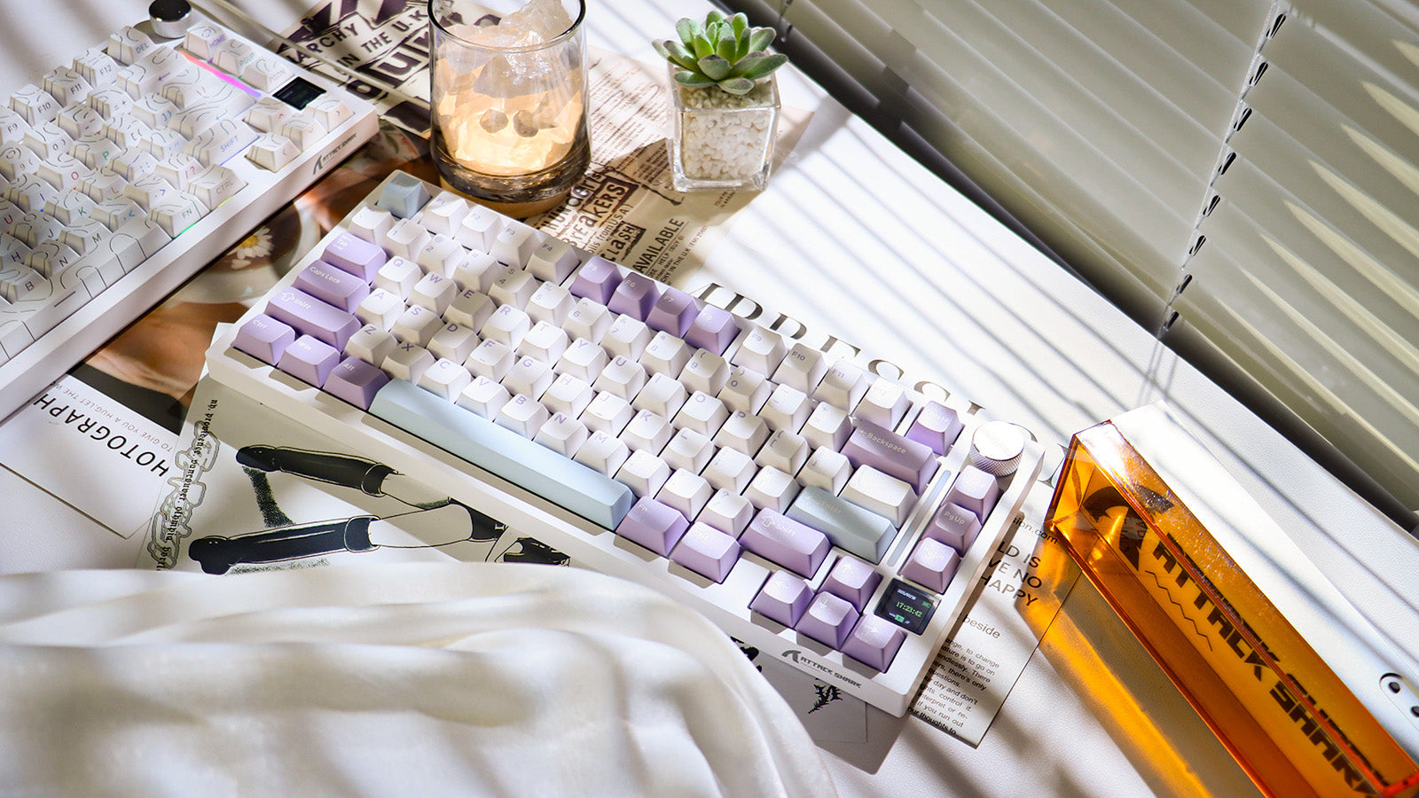 A white 75% mechanical keyboard with white and purple keycaps on a newspaper or magazine